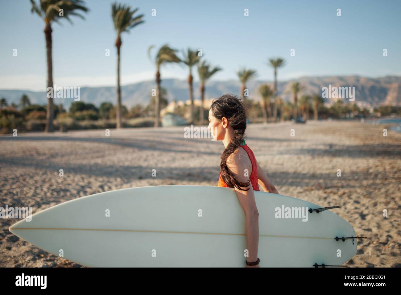 Jeune femme marchant à travers la plage avec son planche de surf Banque D'Images