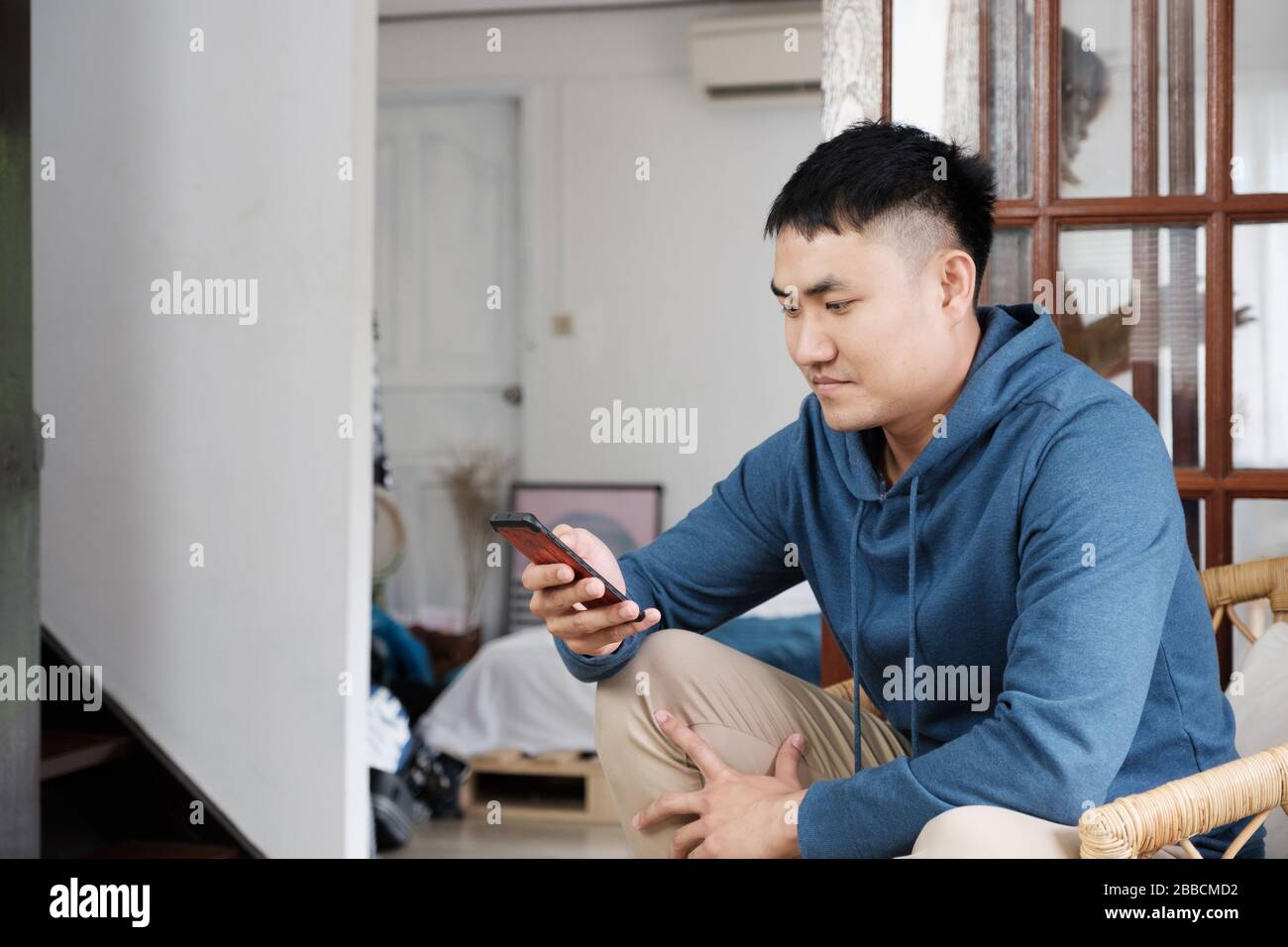 homme asiatique utilisant internet mobile de surf et les médias sociaux à la maison en week-end.travail de la maison.rester sûr à la maison Banque D'Images