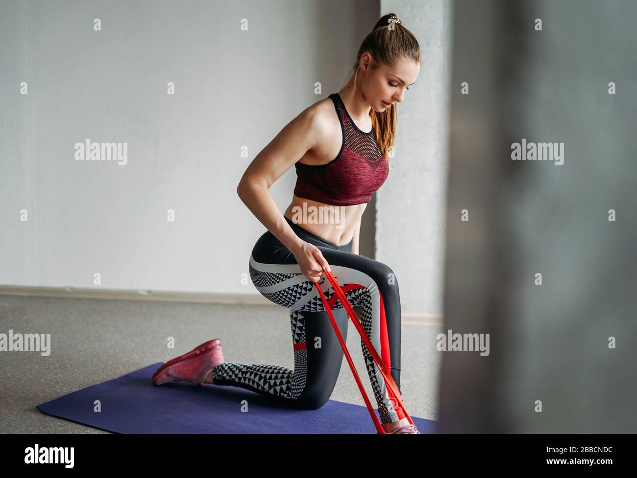 Tenue attrayante jeune femme sport porter modèle de fille de forme physique  s'étirant avec bande élastique à la classe d'entraînement de studio de loft  Photo Stock - Alamy