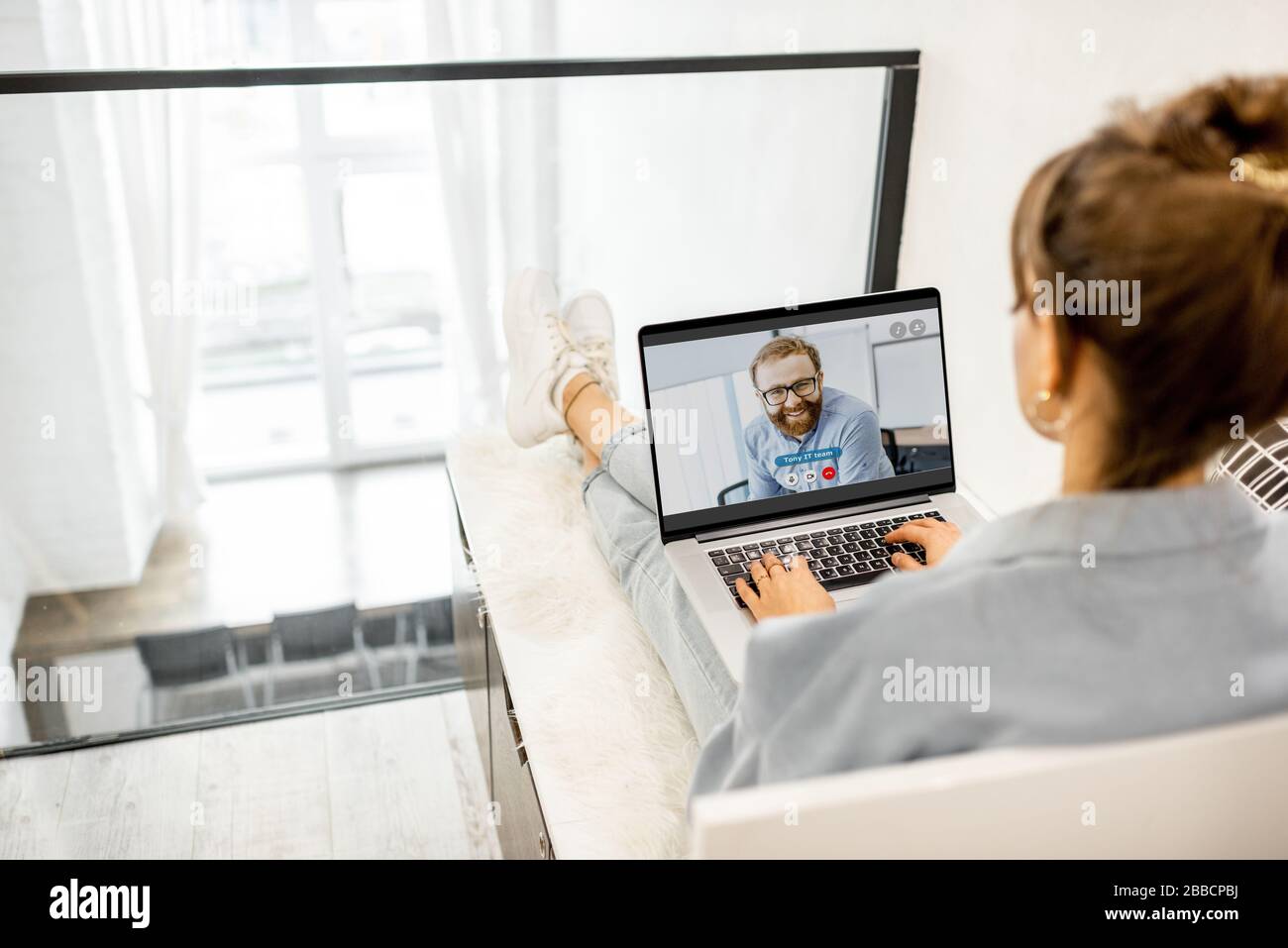Femme d'affaires ayant un appel vidéo avec un collègue, travaillant en ligne à partir de la maison à l'atmosphère confortable Banque D'Images