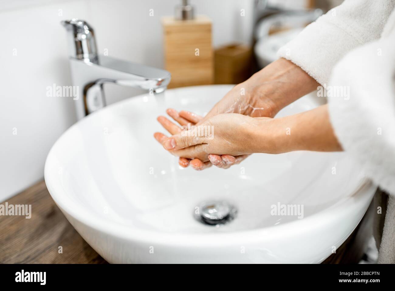 Femme se laver les mains avec un savon à la salle de bains, en prenant soin de l'hygiène, gros plan sur les mains Banque D'Images
