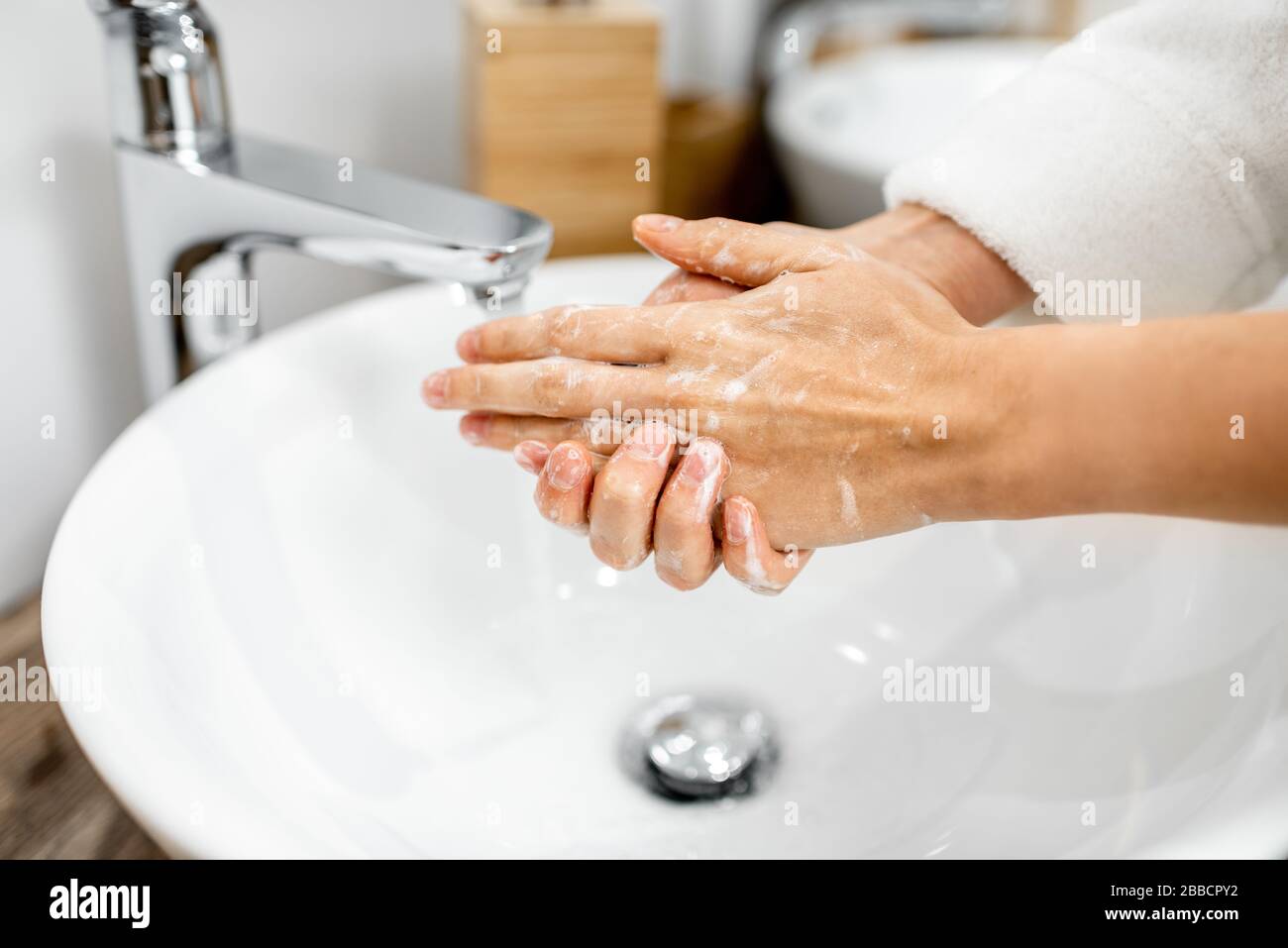 Femme se laver les mains avec un savon à la salle de bains, en prenant soin de l'hygiène, gros plan sur les mains Banque D'Images