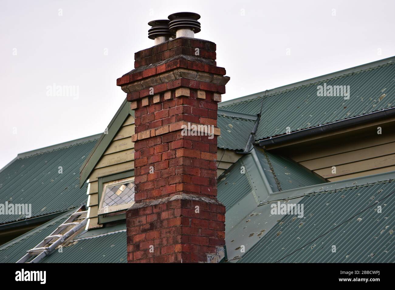 Cheminée en brique vintage sur la vieille maison avec toit en fer ondulé. Banque D'Images