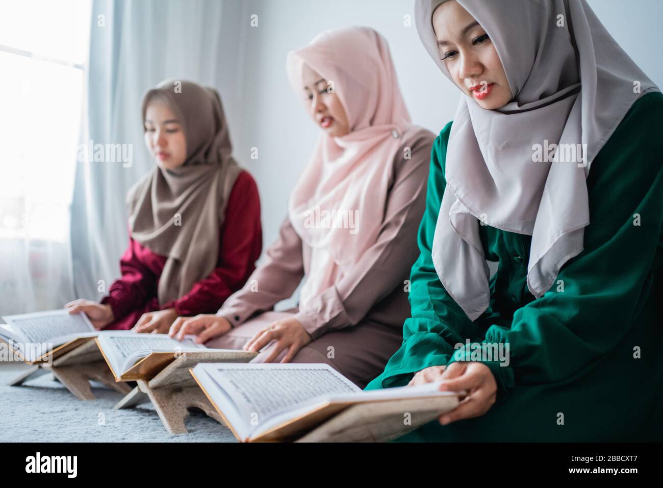 Trois musulmans asiatiques lisent et apprennent le livre Saint de l'Al-Quran ensemble assis à l'étage dans la chambre Banque D'Images