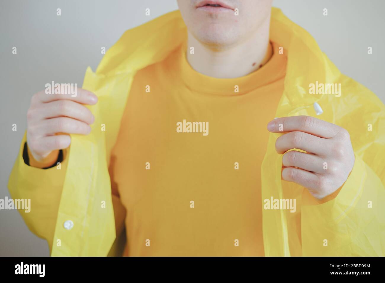 Homme en t-shirt jaune et imperméable. Parties du corps de l'homme, couleurs vives jaunes Banque D'Images