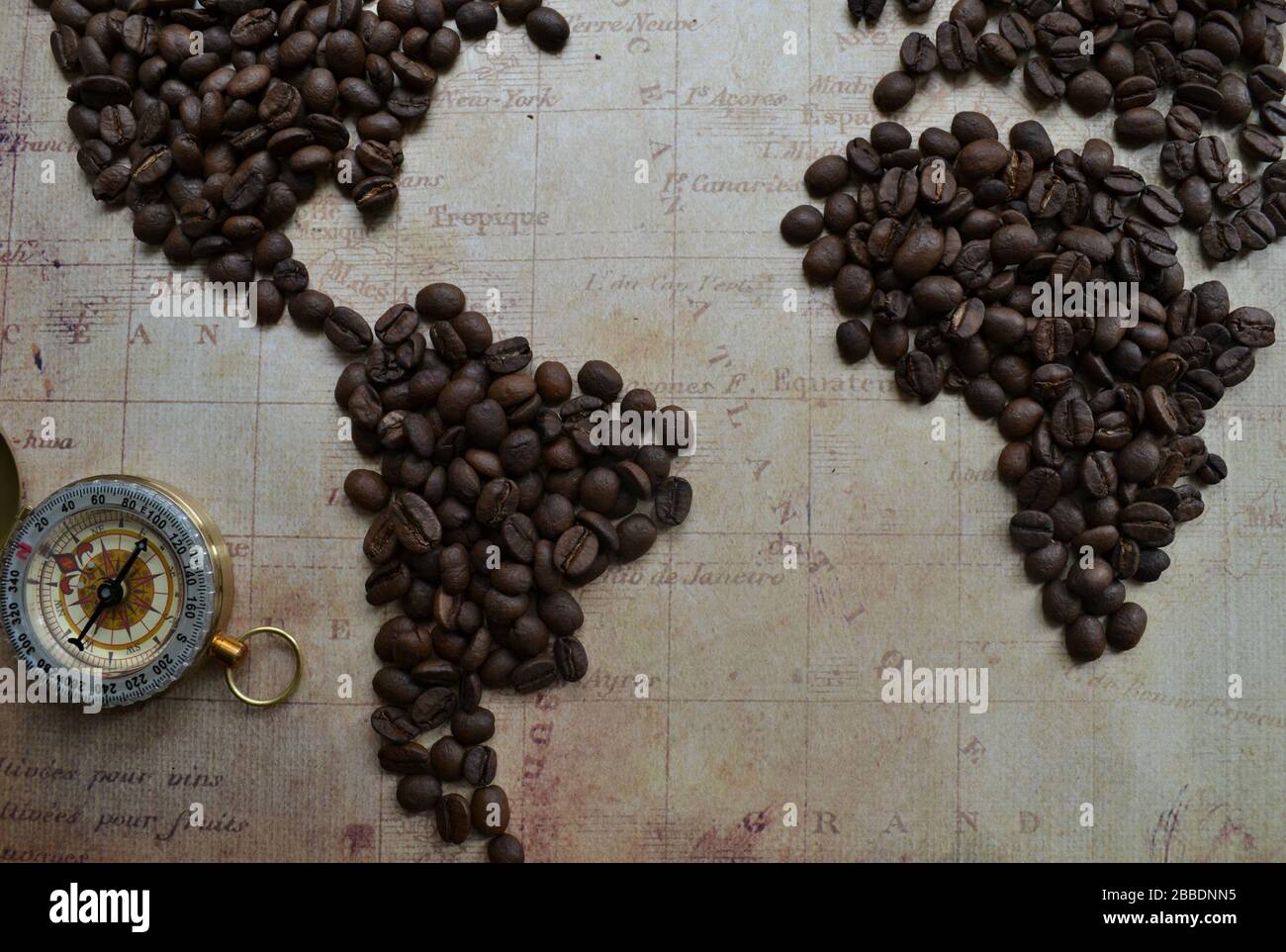 Un monde plat de grains de café sur l'arrière-plan de la carte avec un ancien compas en laiton Banque D'Images