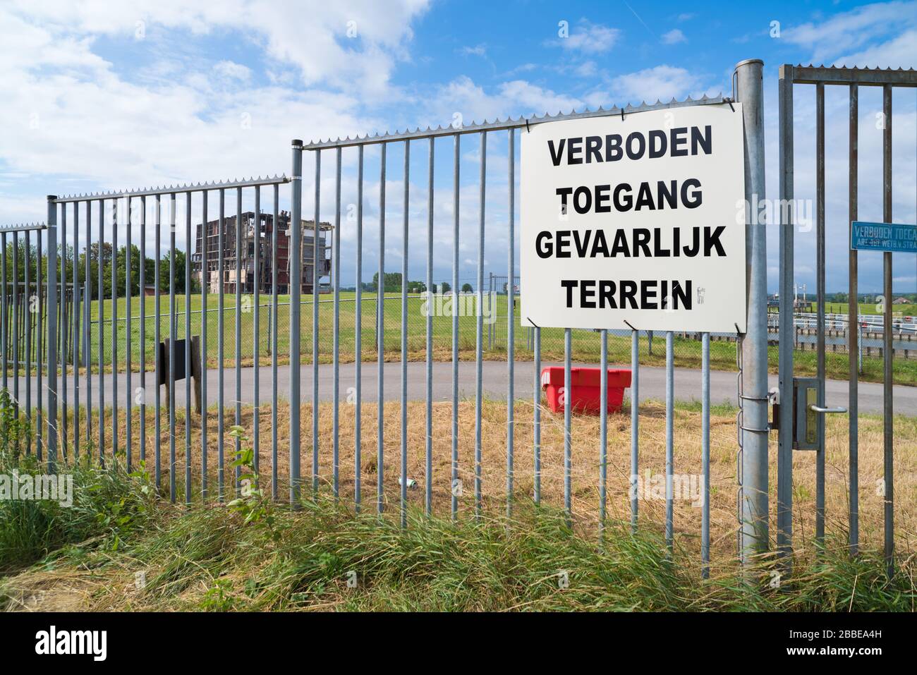 pas de terrein, zone dangereuse (verboden toegang, gevaarlijk terrein en néerlandais) sur une clôture métallique devant une ruine d'une ancienne usine Banque D'Images