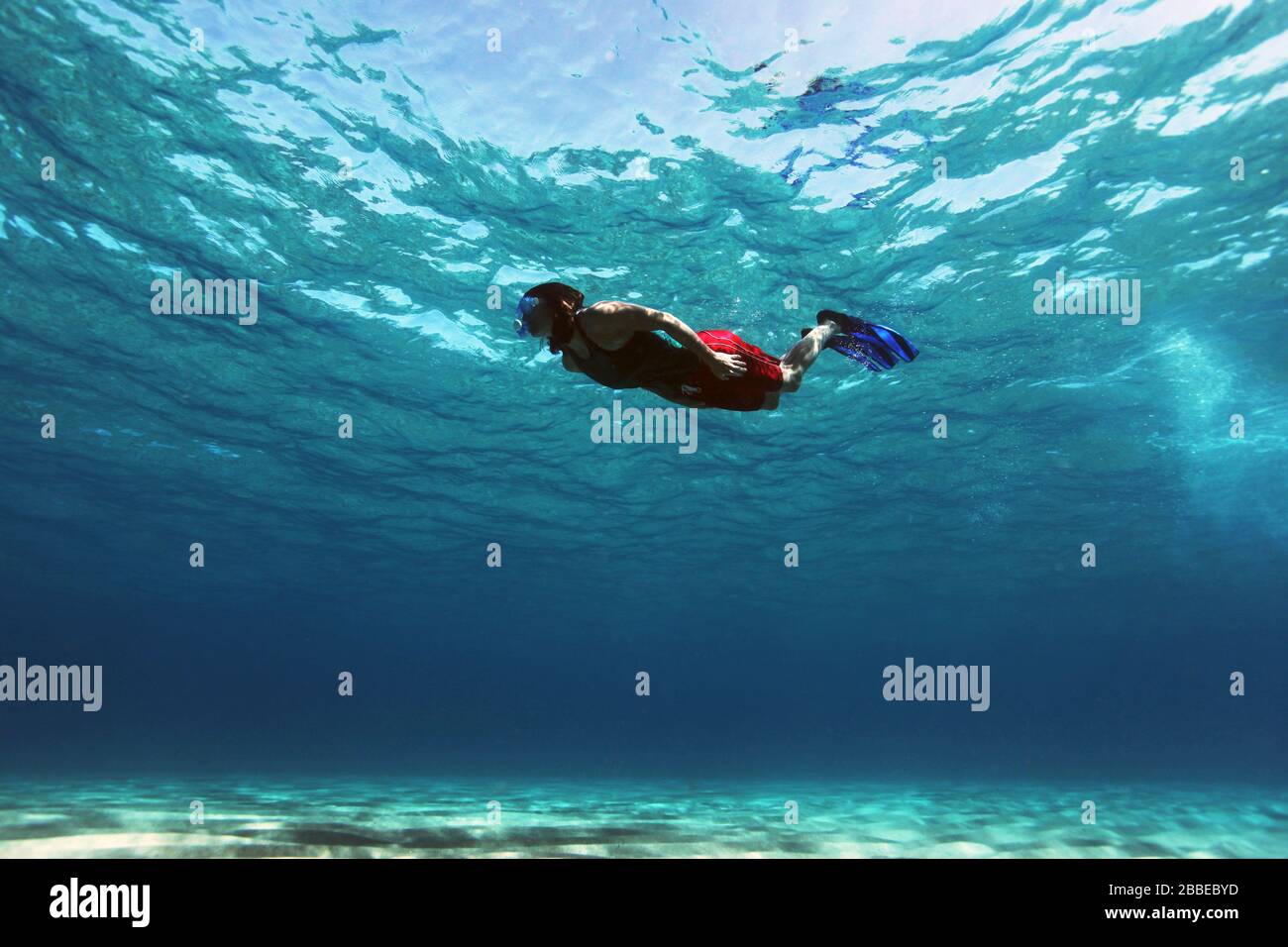 Une jeune femme nageant dans les eaux peu profondes et claires de Cala Gonone, en Sardaigne. Banque D'Images