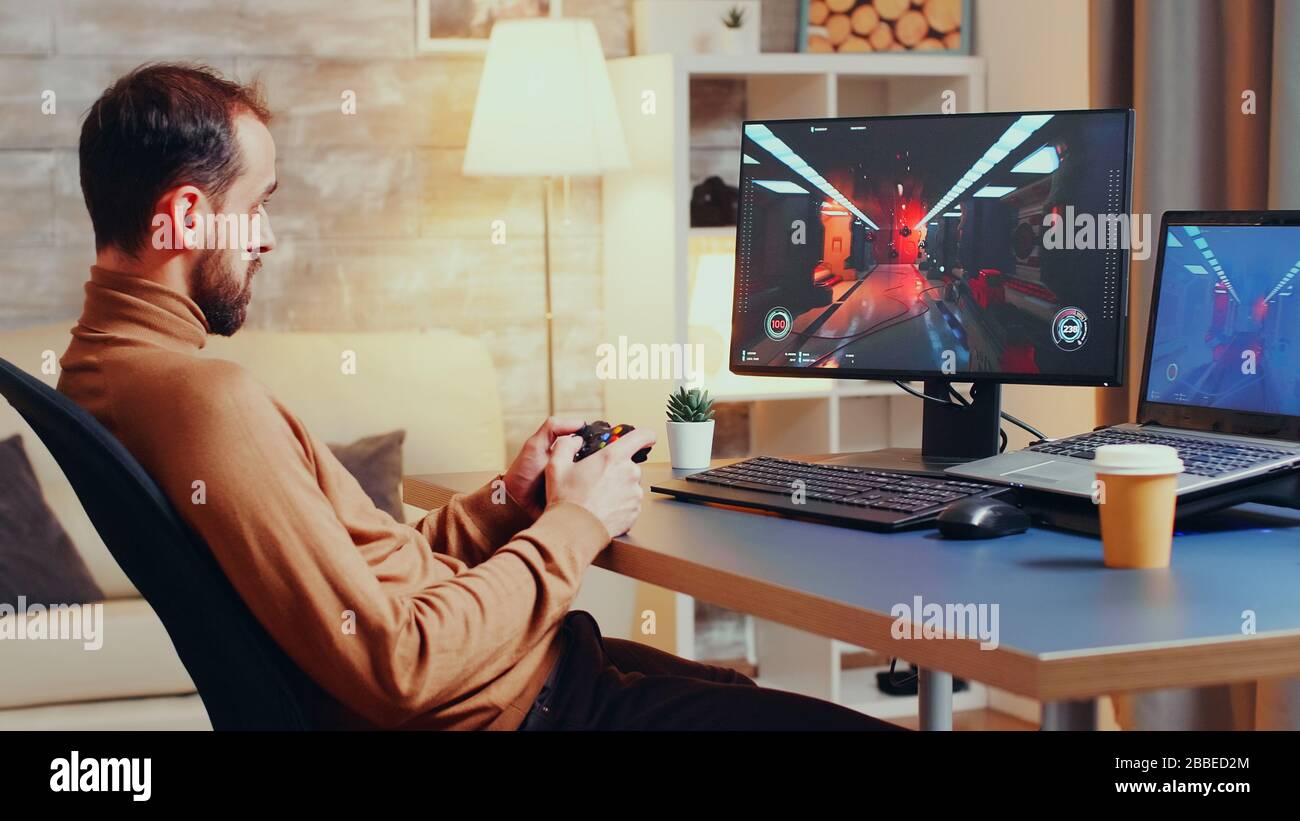 Développeur de jeux testant un nouveau joystick pour le jeu de tir à partir du bureau à domicile la nuit. Banque D'Images
