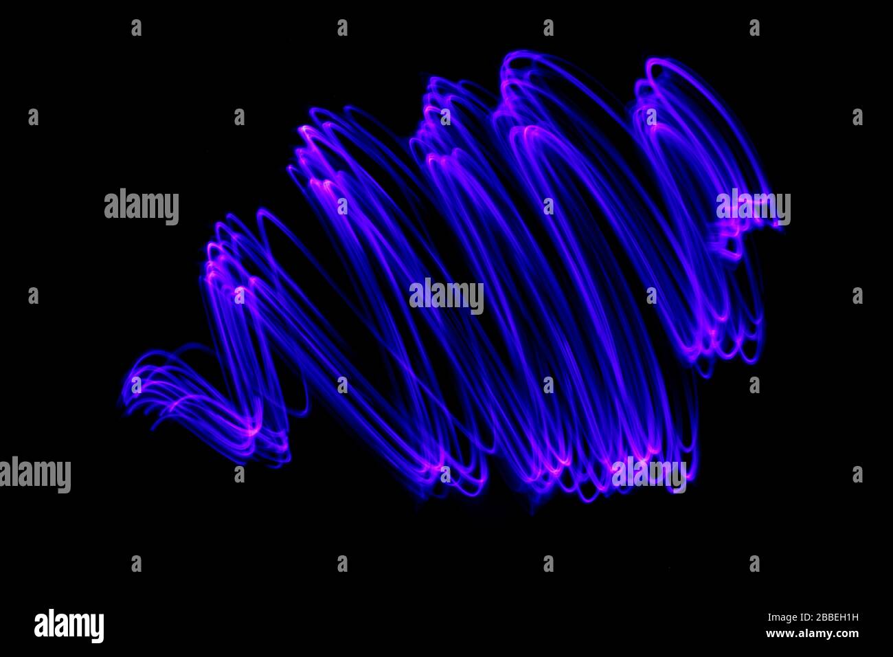 Photographie de longue exposition de couleur néon vive dans un tourbillon abstrait, lignes parallèles modèle contre un fond noir. Photographie de peinture légère. Banque D'Images