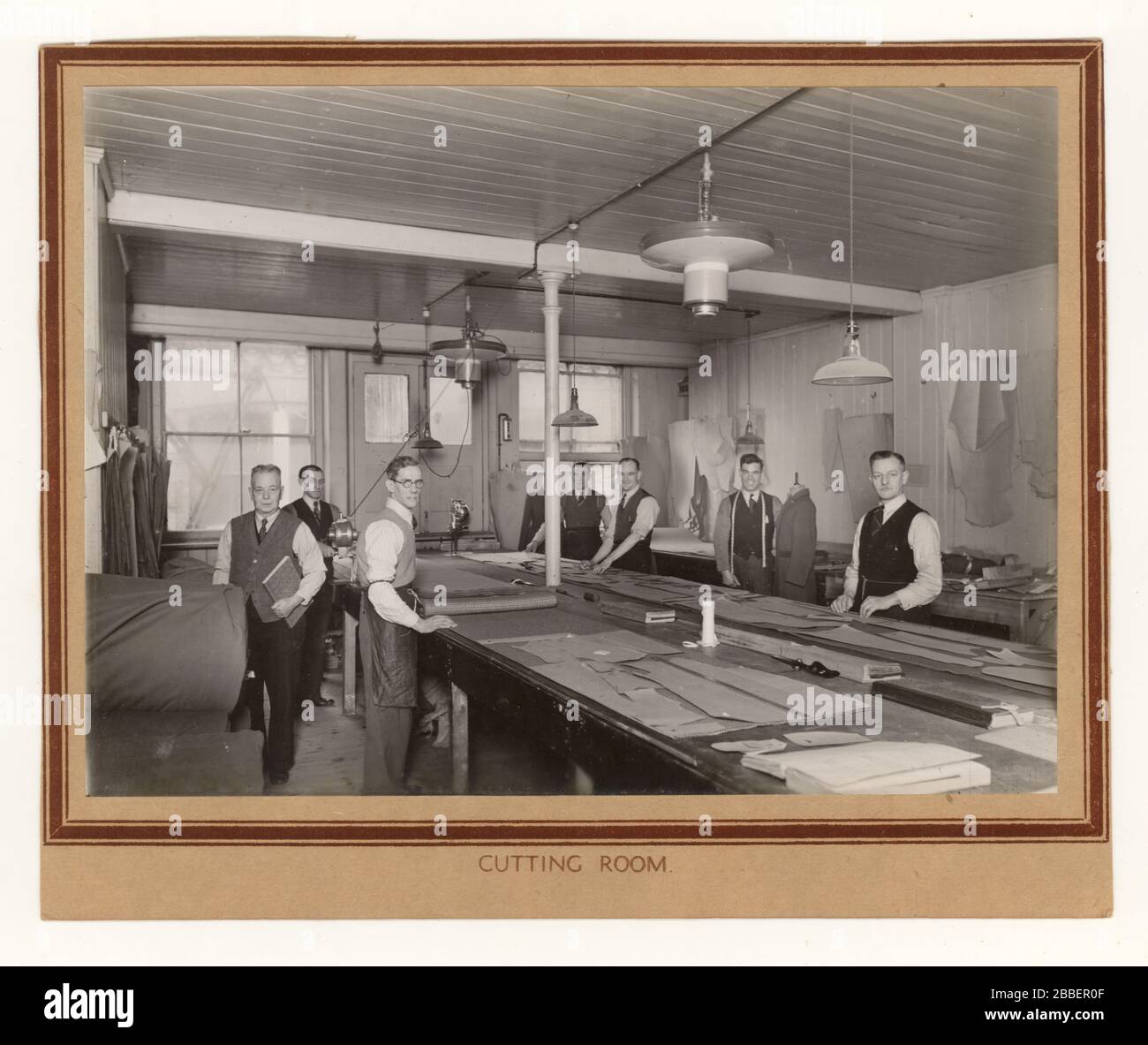 Photo originale du début des années 1900 d'hommes au travail dans la salle de coupe d'une usine de vêtements, en utilisant des motifs, en faisant des costumes de laine de tweed, vers les années 1930 des années 1940, probablement Norwich, Angleterre, Royaume-Uni Banque D'Images