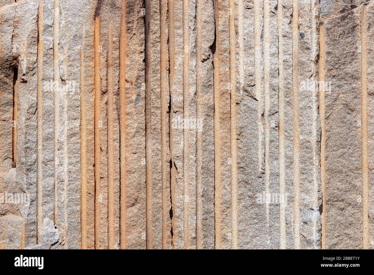 Une série de lignes verticales dans une falaise dans une carrière de roche. Les lignes ont été formées par des foreuses utilisées pour séparer le visage de la roche de la falaise. Soleil brillant Banque D'Images