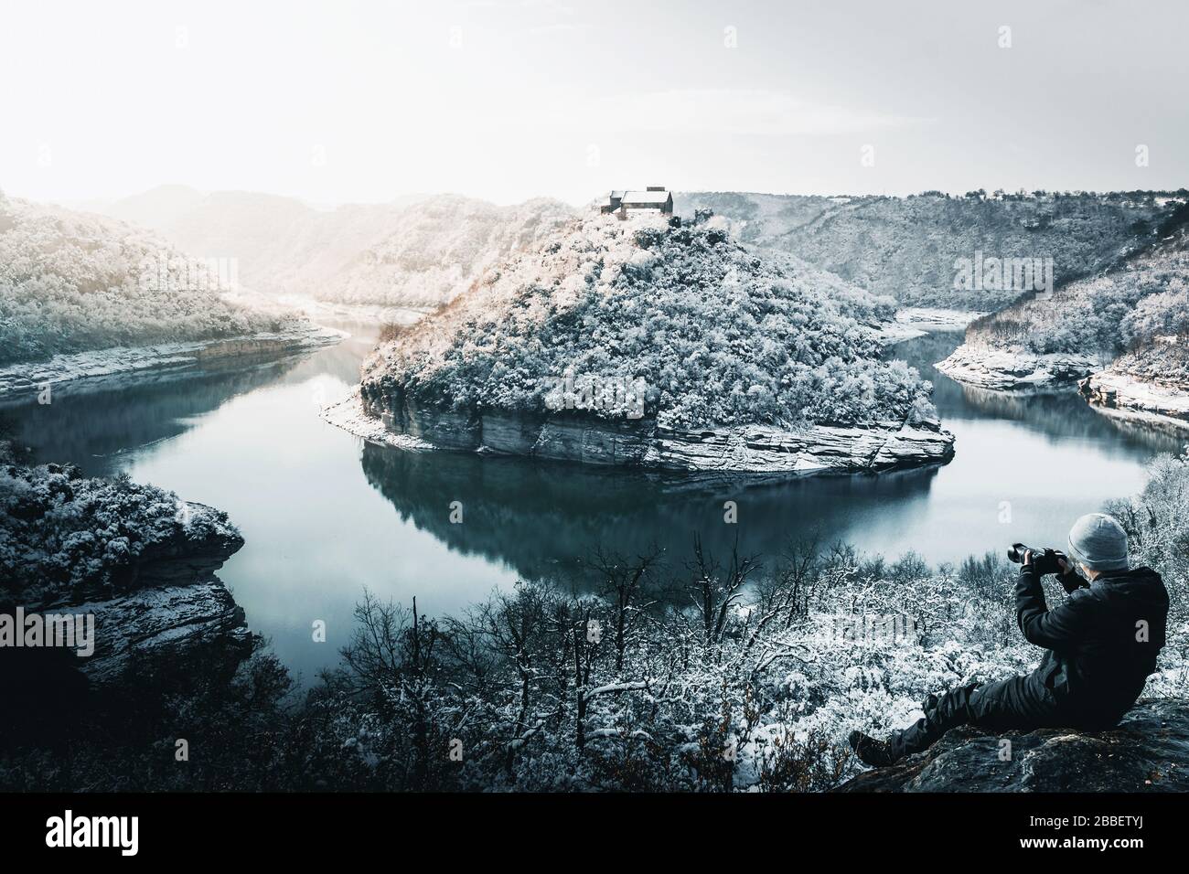 Photographe prenant des photos dans un paysage enneigé d'un méchant de rivière Banque D'Images