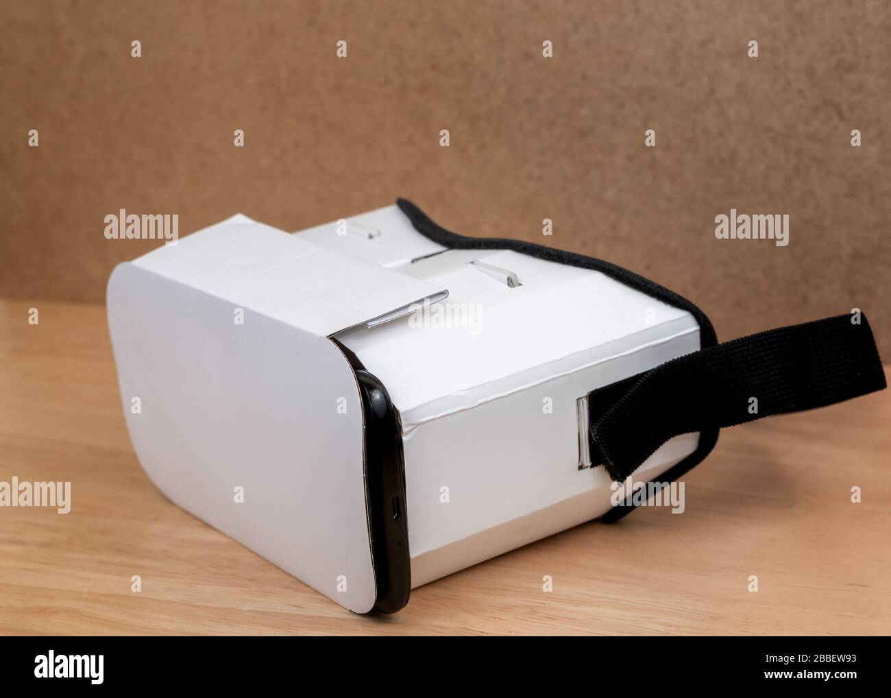 Un casque VR en carton. Vue d'un angle à l'avant. L'avant est fermé et le bord du téléphone mobile inséré est visible. Il est sur un WO Banque D'Images