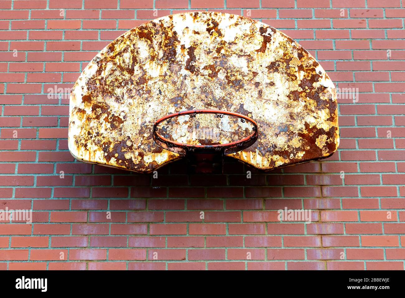 Un ancien panier de basket-ball monté à l'extérieur sur un mur de briques. Le filet est parti, et le panneau arrière est sale et rouillé. Espace pour le texte. Banque D'Images
