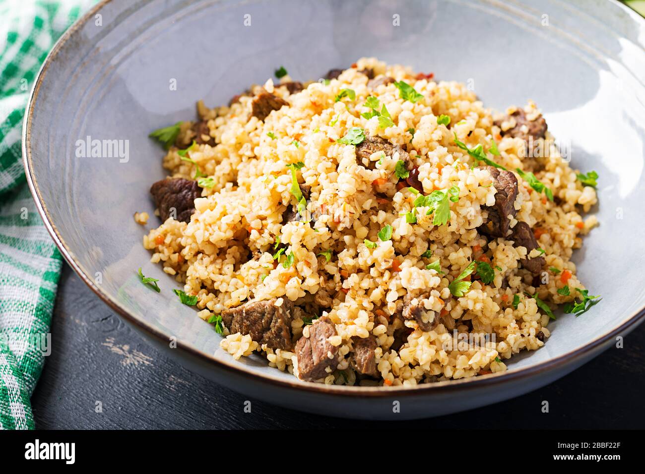 Bubgur pilaf avec viande et légumes. Délicieux déjeuner chaud et sain sur fond noir. Cuisine orientale. Banque D'Images