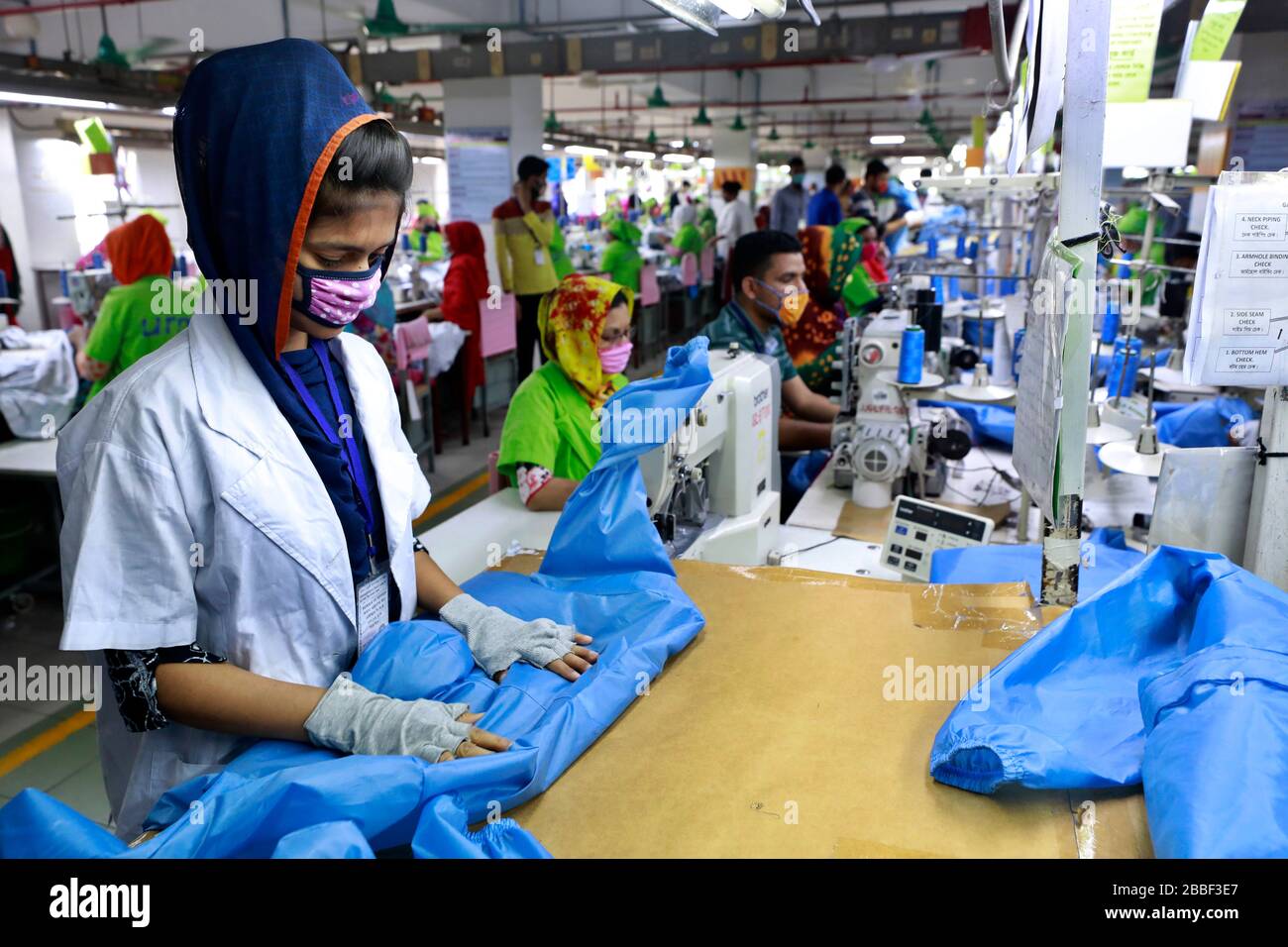 Dhaka, Bangladesh - 31 mars 2020: Travailleurs produisant des équipements de protection individuelle (EPI) pour les professionnels de la santé dans une usine de vêtements du groupe Urmi Banque D'Images