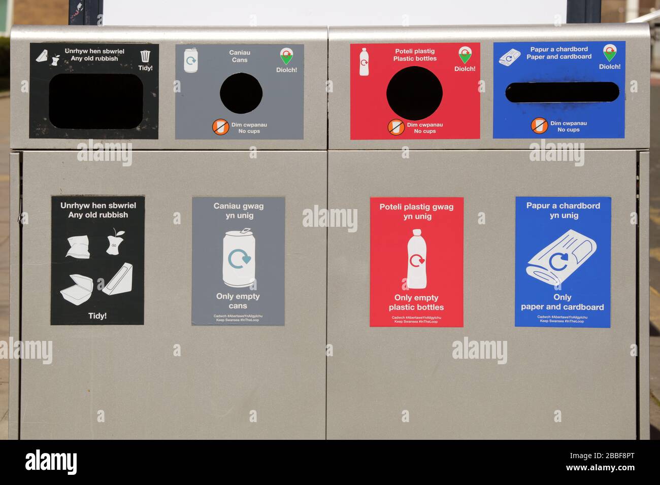 Bacs de recyclage publics avec compartiments pour poubelles, boîtes, bouteilles, papier et carton. Anglais et gallois. Banque D'Images
