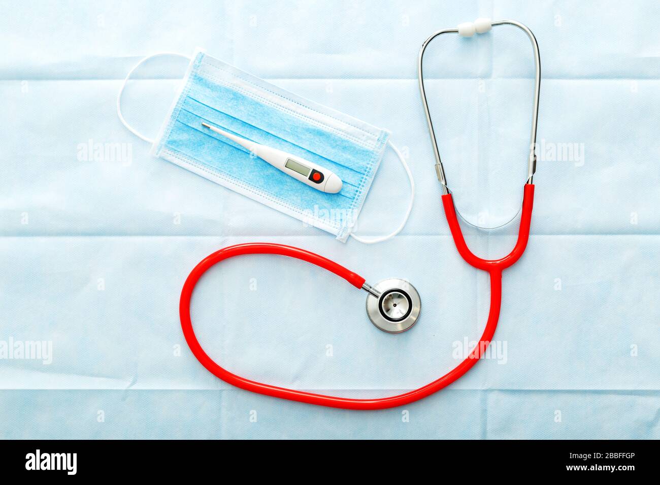 Thermomètre de masque médical stéthoscope rouge, masque de protection chirurgical sur fond bleu. Médecins équipement professionnel. Concept médical de santé Banque D'Images
