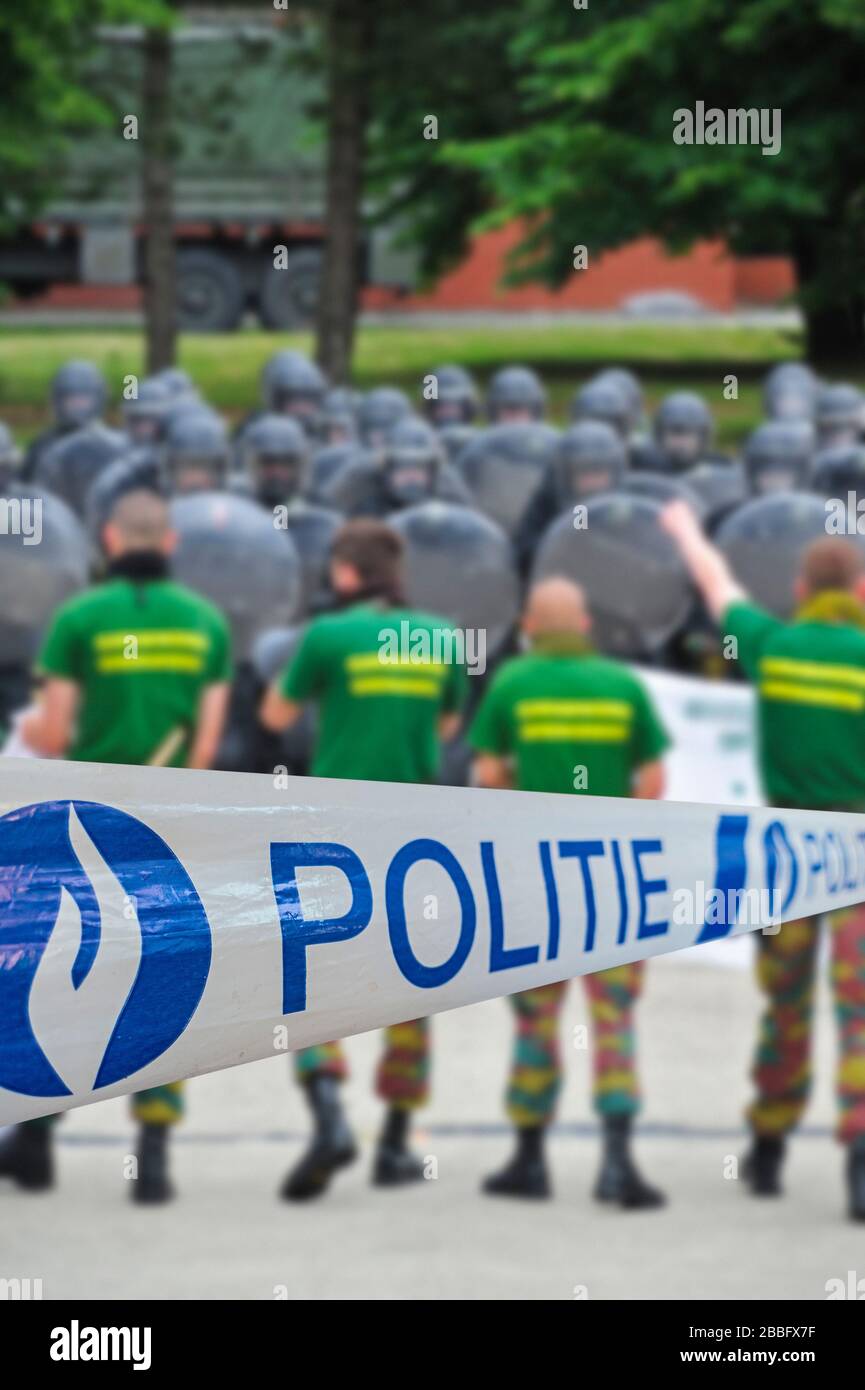 Ruban politié / policier devant les manifestants et l'escadron belge de riot formant une barrière protectrice avec des boucliers anti-émeutes Banque D'Images