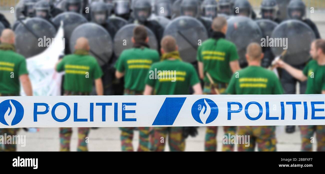 Ruban politié / policier devant les manifestants et l'escadron belge de riot formant une barrière protectrice avec des boucliers anti-émeutes Banque D'Images