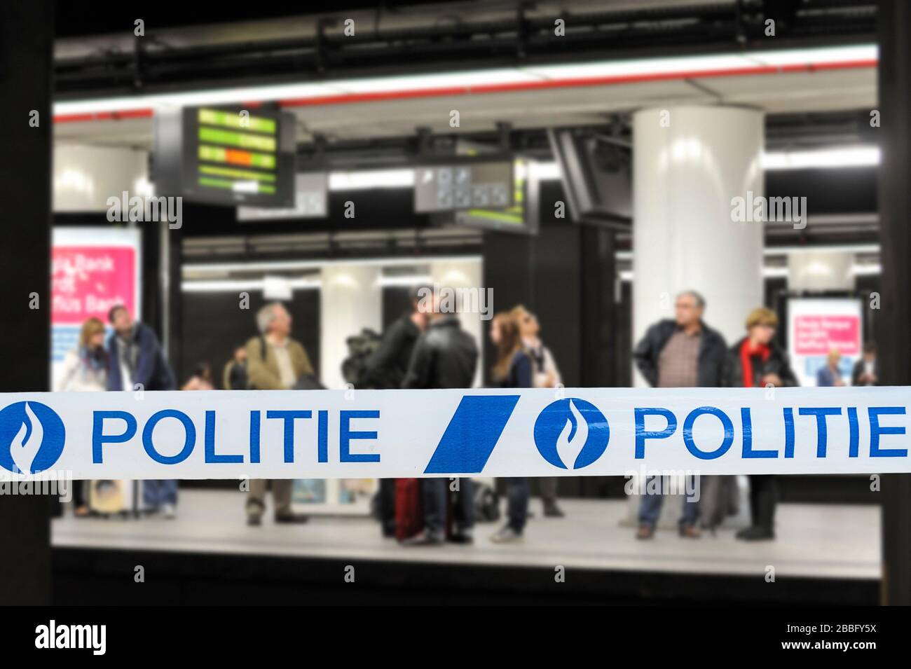 Ruban de police / Politie devant les navetteurs attendant le train à la plate-forme de la gare belge en Belgique Banque D'Images