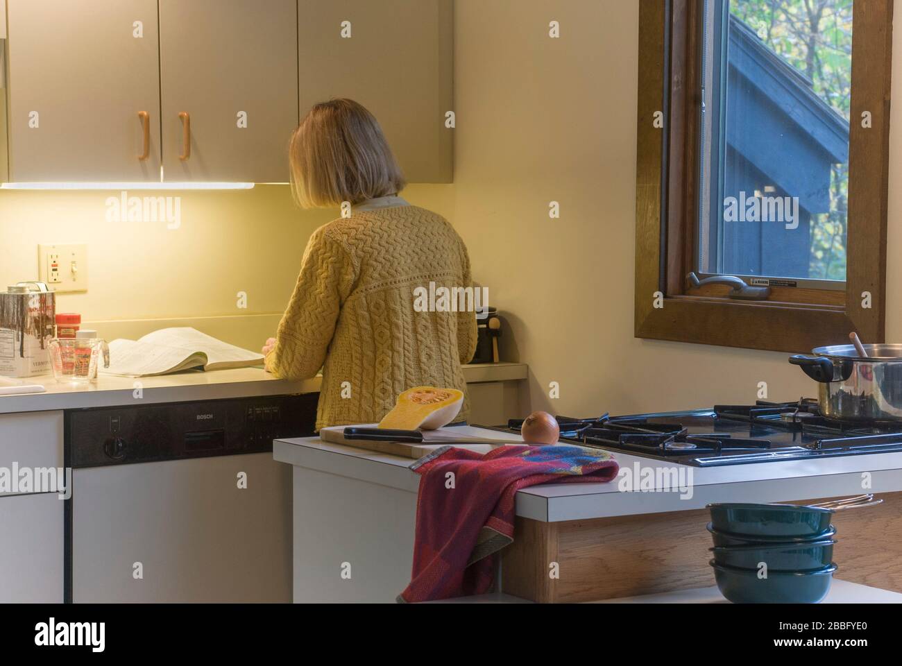 Femme dans la cuisine avec table de cuisson à gaz à quatre brûleurs préparant la soupe de courge musquée Banque D'Images