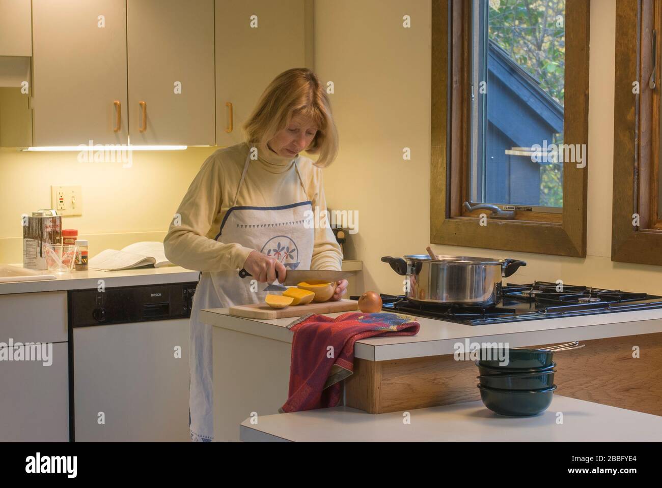 Femme dans la cuisine avec table de cuisson à gaz à quatre brûleurs préparant la soupe de courge musquée Banque D'Images