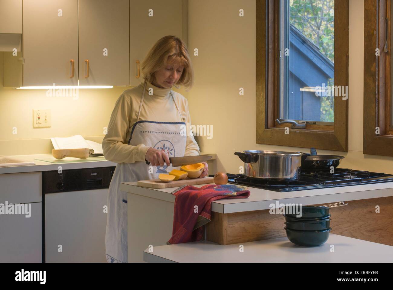 Femme dans la cuisine avec table de cuisson à gaz à quatre brûleurs préparant la soupe de courge musquée Banque D'Images