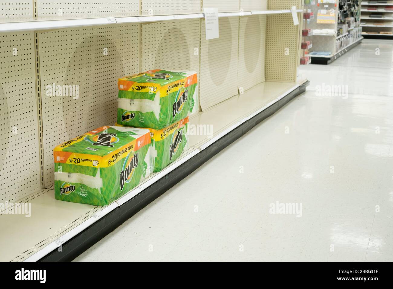Indiana, États-Unis - 24 mars 2020: Trois paquets de serviettes en papier restent sur des étagères vides dans le magasin cible où les panneaux sont postés limite p Banque D'Images