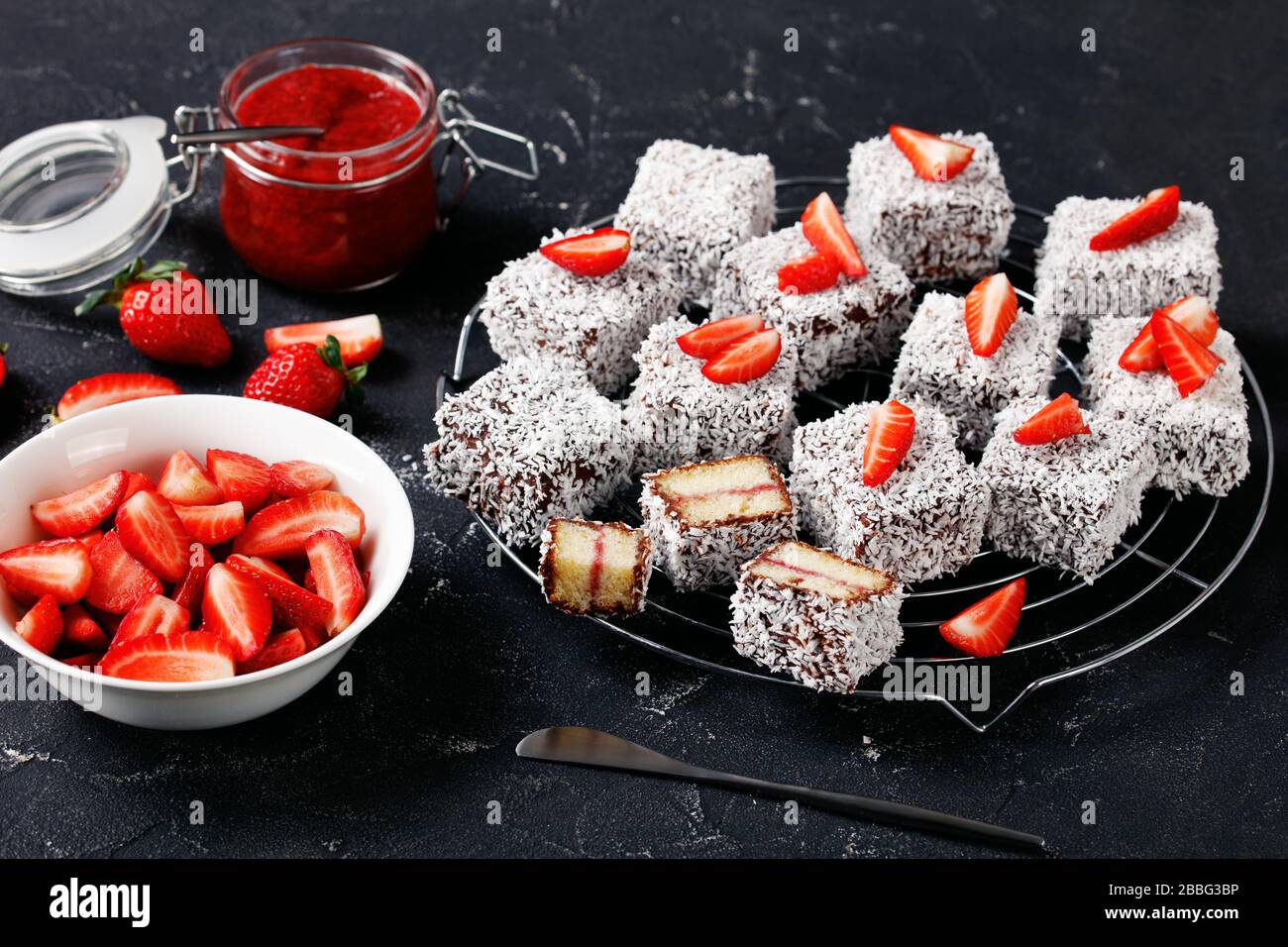 Le célèbre dessert australien : lamingtons avec remplissage de confiture de fraises, enrobés de chocolat et de noix de coco râpée, servis sur une grille en fil rond dans une coquette sombre Banque D'Images