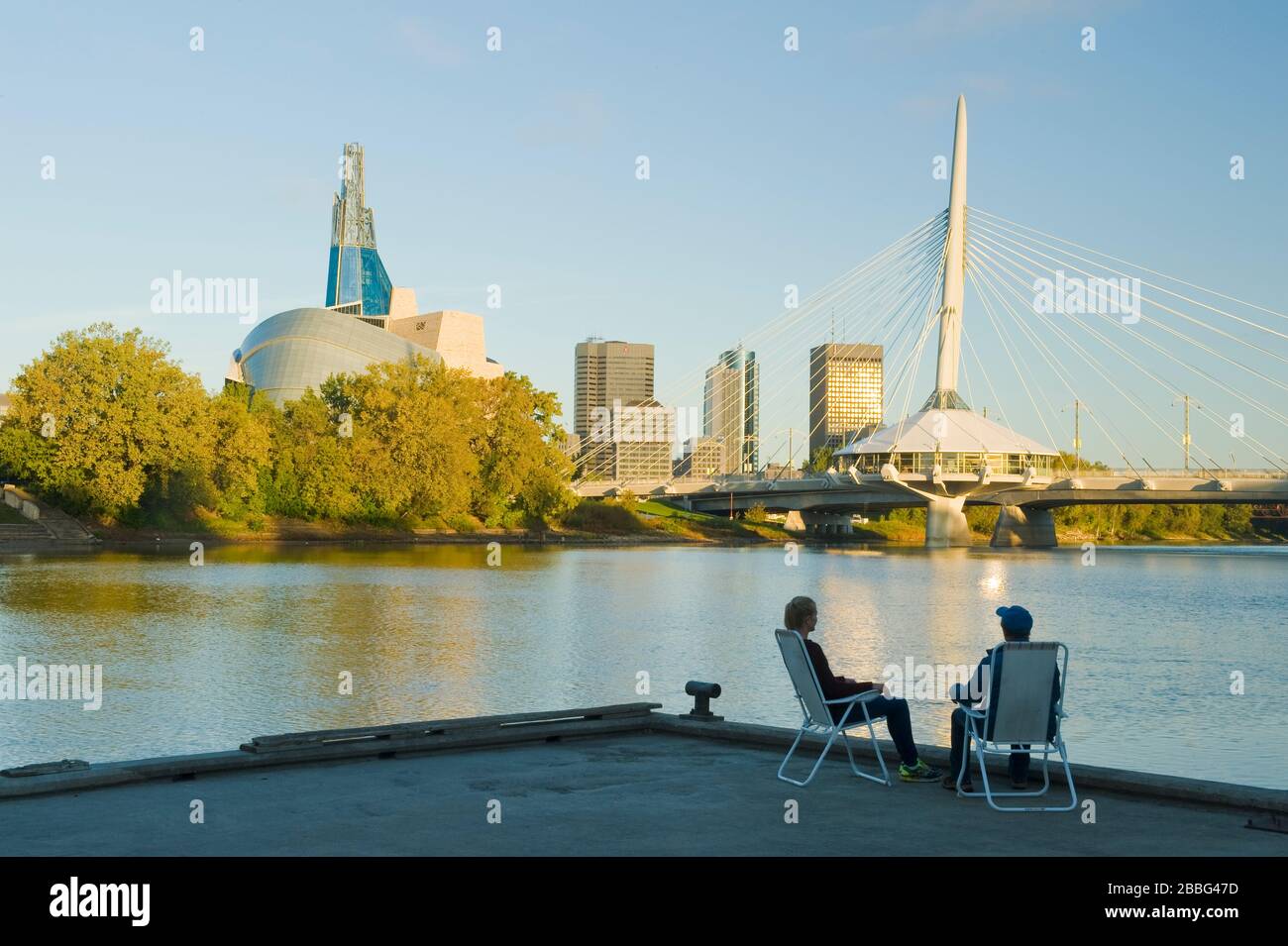 Couple détente, horizon de Winnipeg de Saint-Boniface montrant la rivière Rouge, le pont Esplanade Riel et le Musée canadien des droits de la personne, Manitoba, Canada Banque D'Images