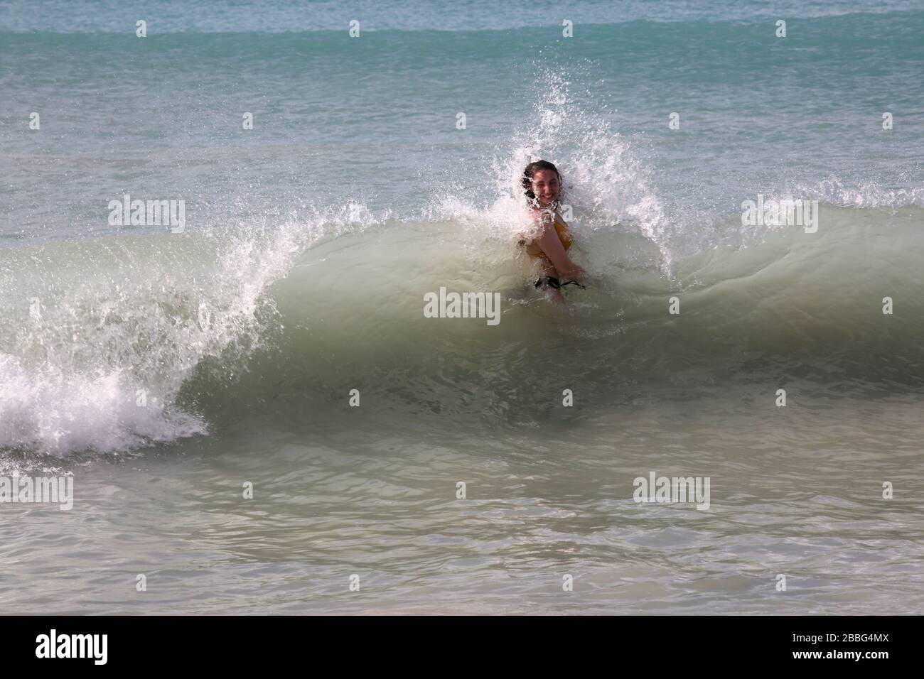 Grande Anse Beach Grenade femme nageant en mer pris dans une vague de rupture Banque D'Images