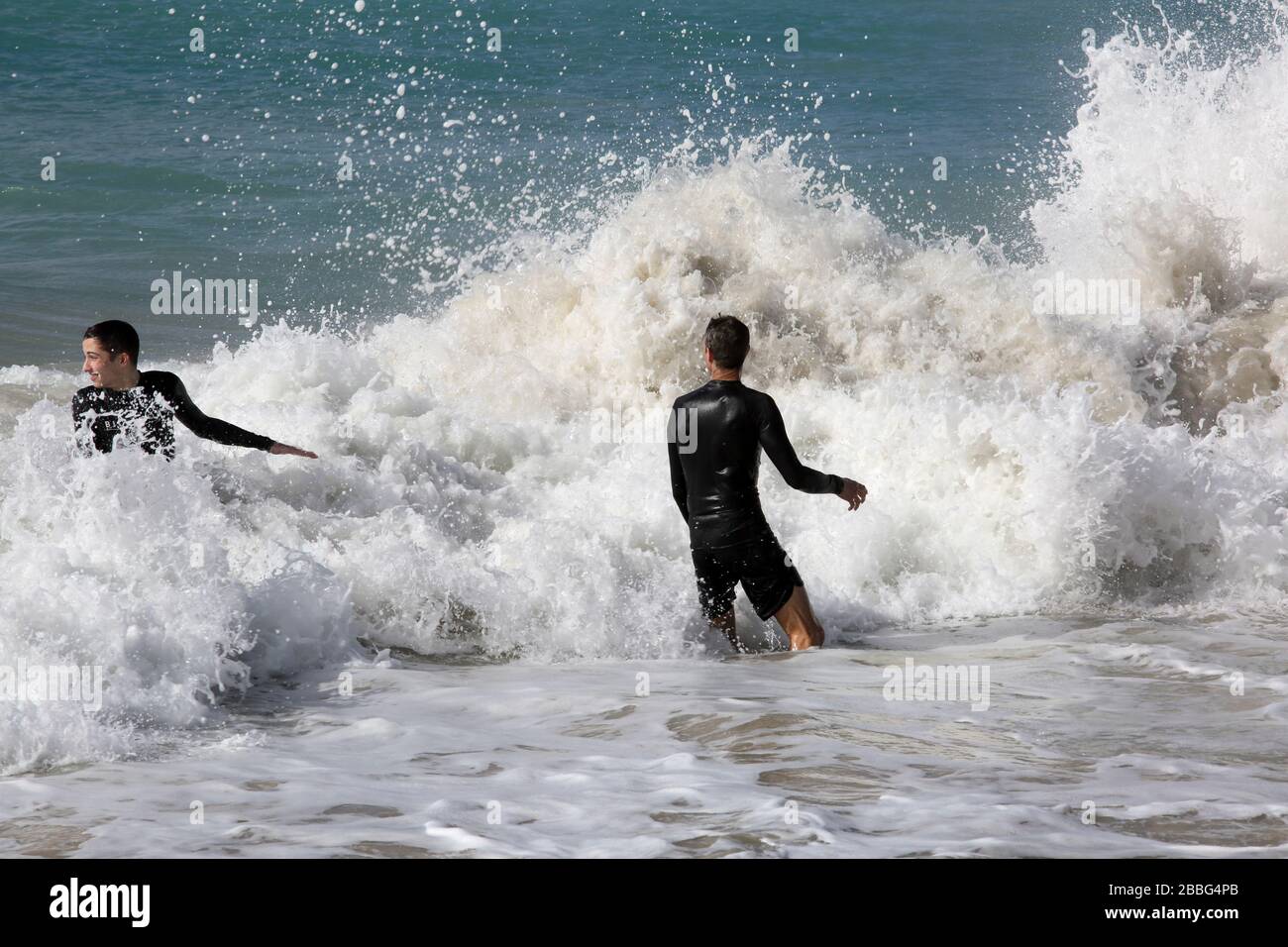 Grand Anse Beach Grenade les hommes en mer pris en brisant les vagues Banque D'Images