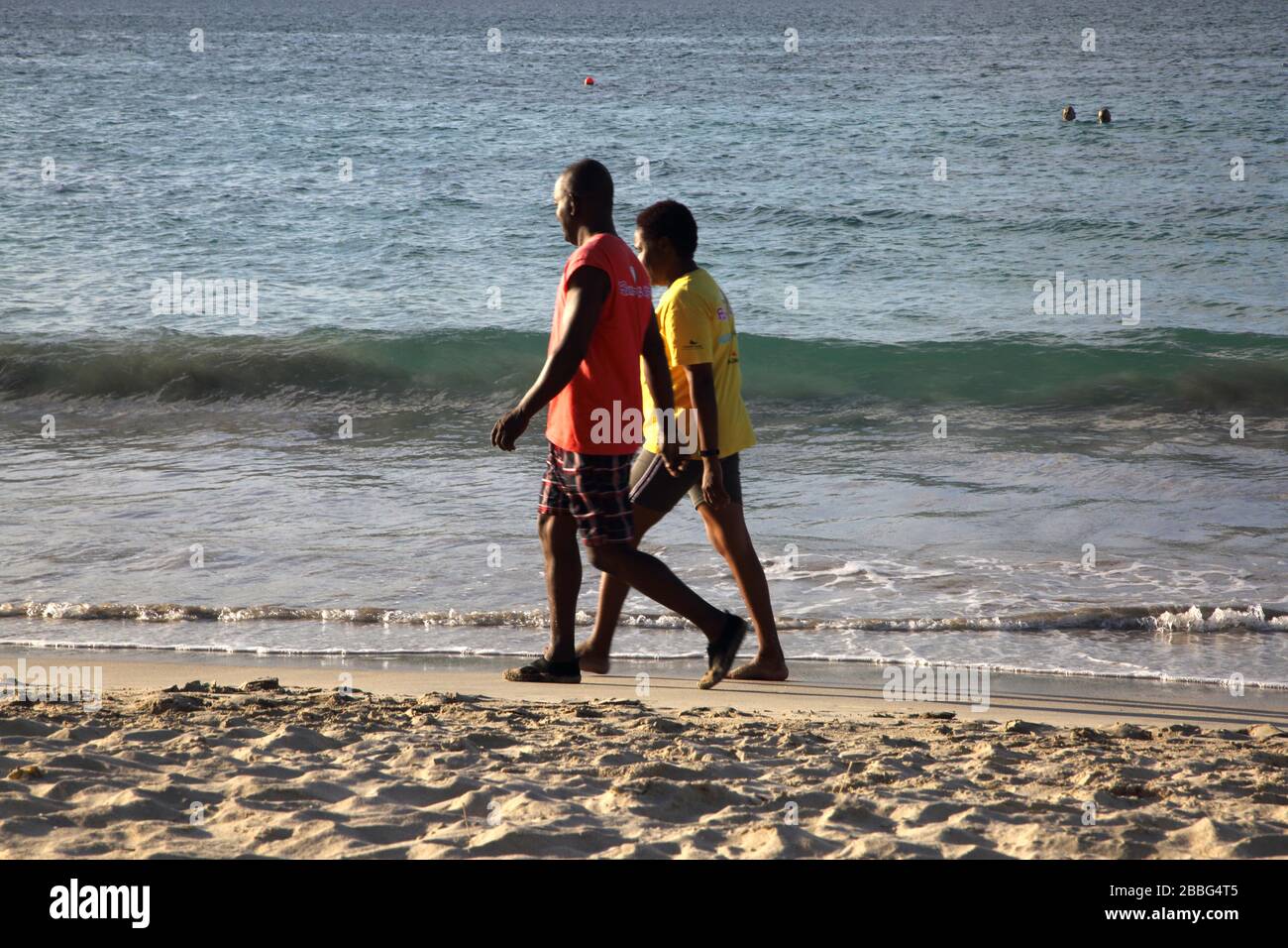 Grenade locaux marchant le long de la plage de Grand Anse Banque D'Images