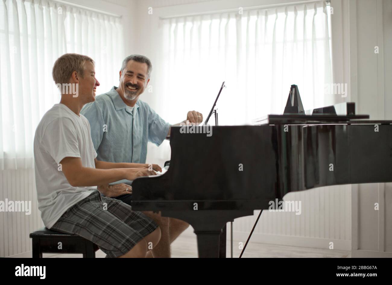 L'adulte l'homme assis à un piano avec son fils adolescent Photo Stock -  Alamy