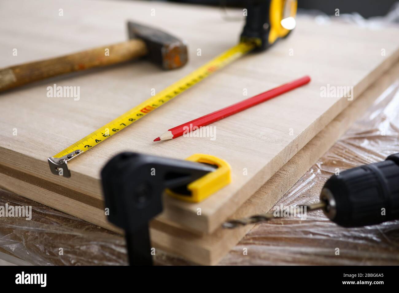 Les outils de charpentier et le foret se trouvent sur la planche en bois Banque D'Images