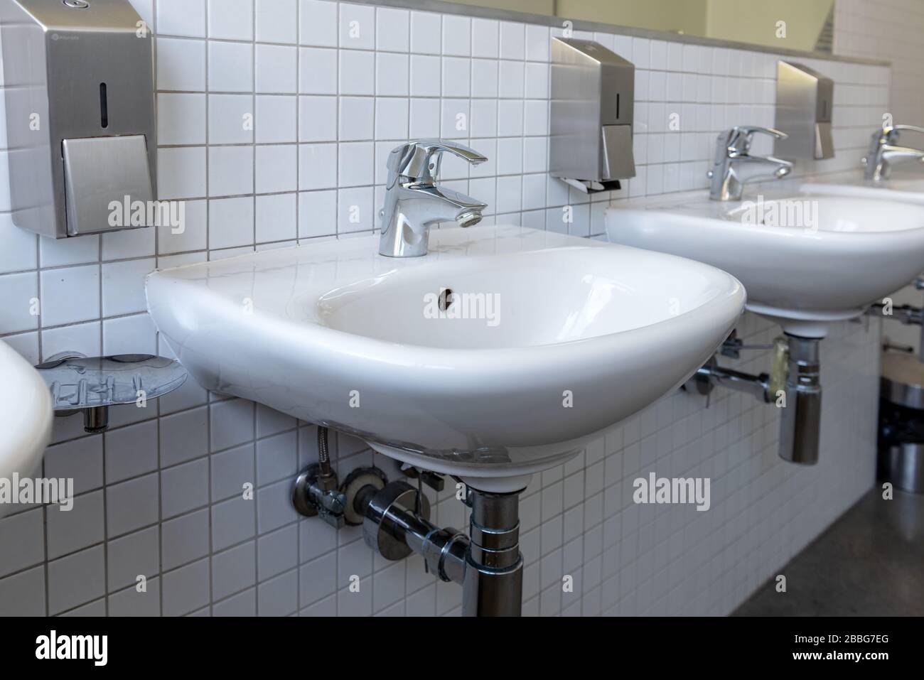 Rangée d'évier en porcelaine blanche dans les toilettes publiques. Concept de protection de l'intégrité antivirus Banque D'Images