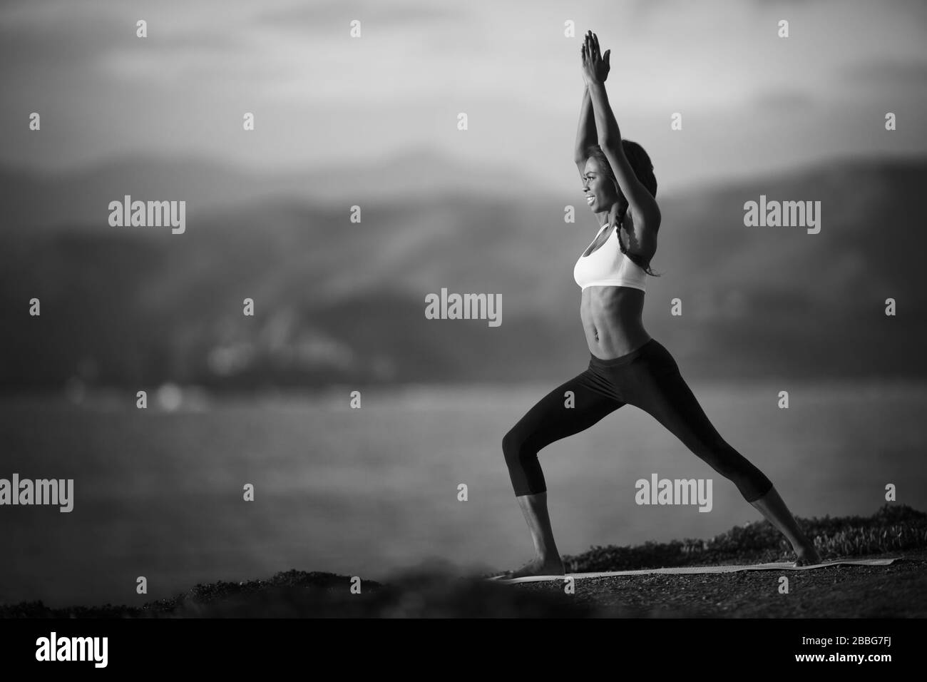 Young woman standing in a yoga pose près d'une côte. Banque D'Images