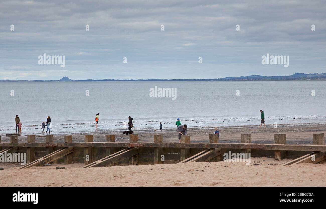 Portobello, Édimbourg, Écosse, Royaume-Uni. 31 mars 2020. Nuageux et calme sur la promenade et la plage plutôt que sur la foule qui fréquente normalement un après-midi, avec peut-être environ 200 personnes la longueur de la plage. Plus comme l'hiver que le printemps avec des arcades d'amusement et des étals de cercueil fermés avec le parc de jeux pour enfants a décollé empêchant quiconque d'entrer en raison de la menace de Coronavirus. Banque D'Images