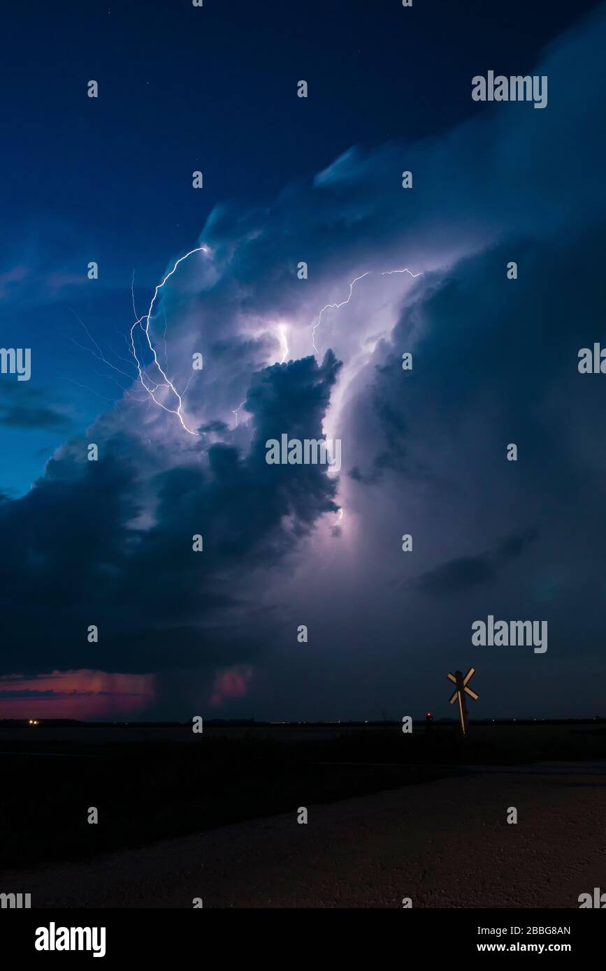 Tempête avec éclair clignotant dans l'arrière-plan d'un panneau de passage de chemin de fer près de Portage la Prairie Manitoba Canada Banque D'Images
