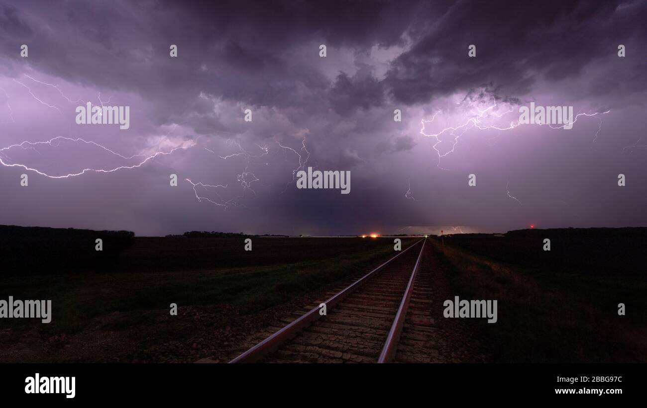 Tempête avec un passage à niveau aérien éclair et des voies ferrées dans le sud du Manitoba, au Canada Banque D'Images