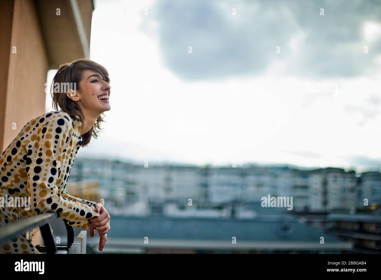 Portrait d'une jeune femme magnifique penchant sur un balcon donnant sur la ville Banque D'Images