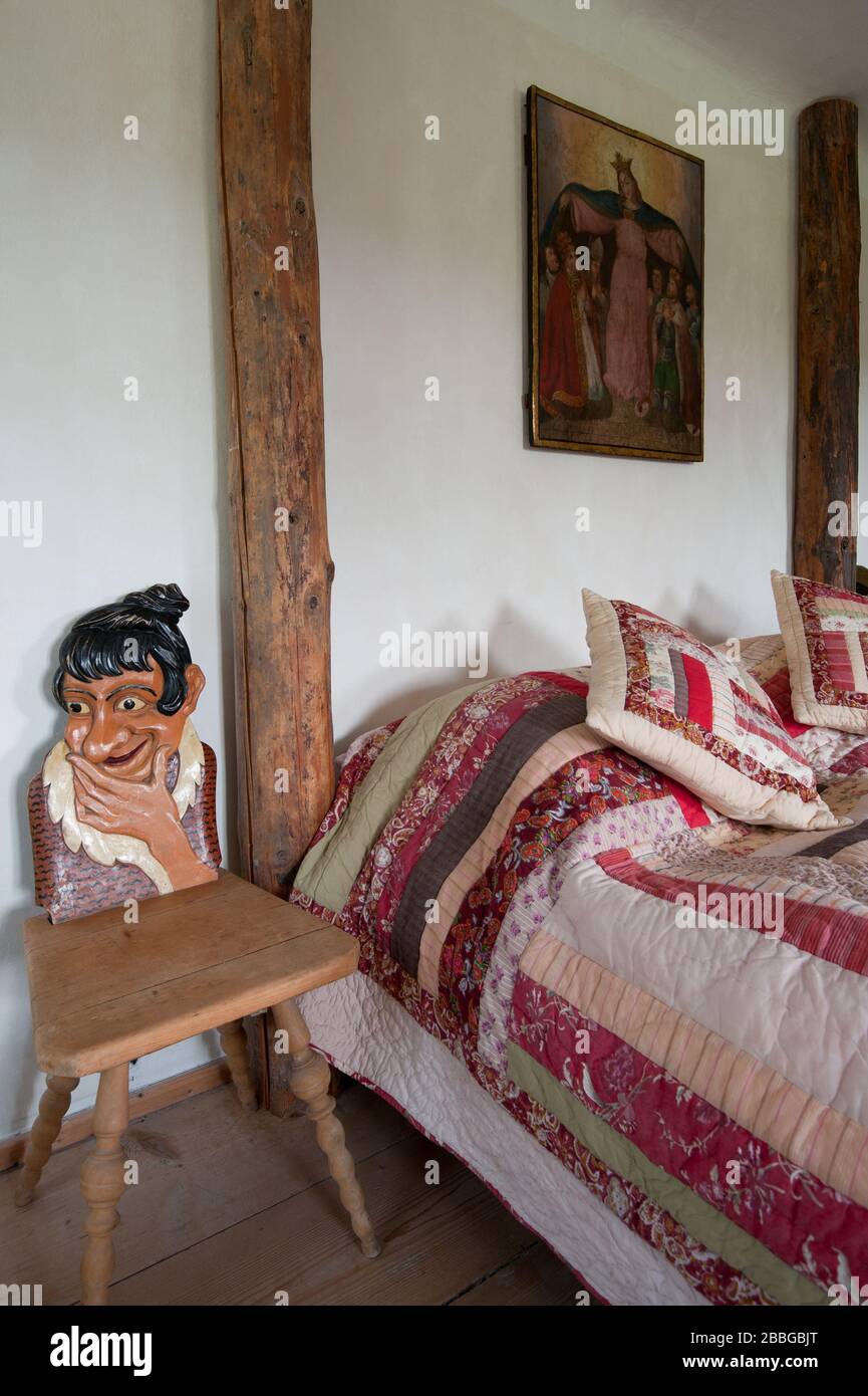 lit avec couvre-lit matelassé et deux chaises sculptées dans la ferme Banque D'Images