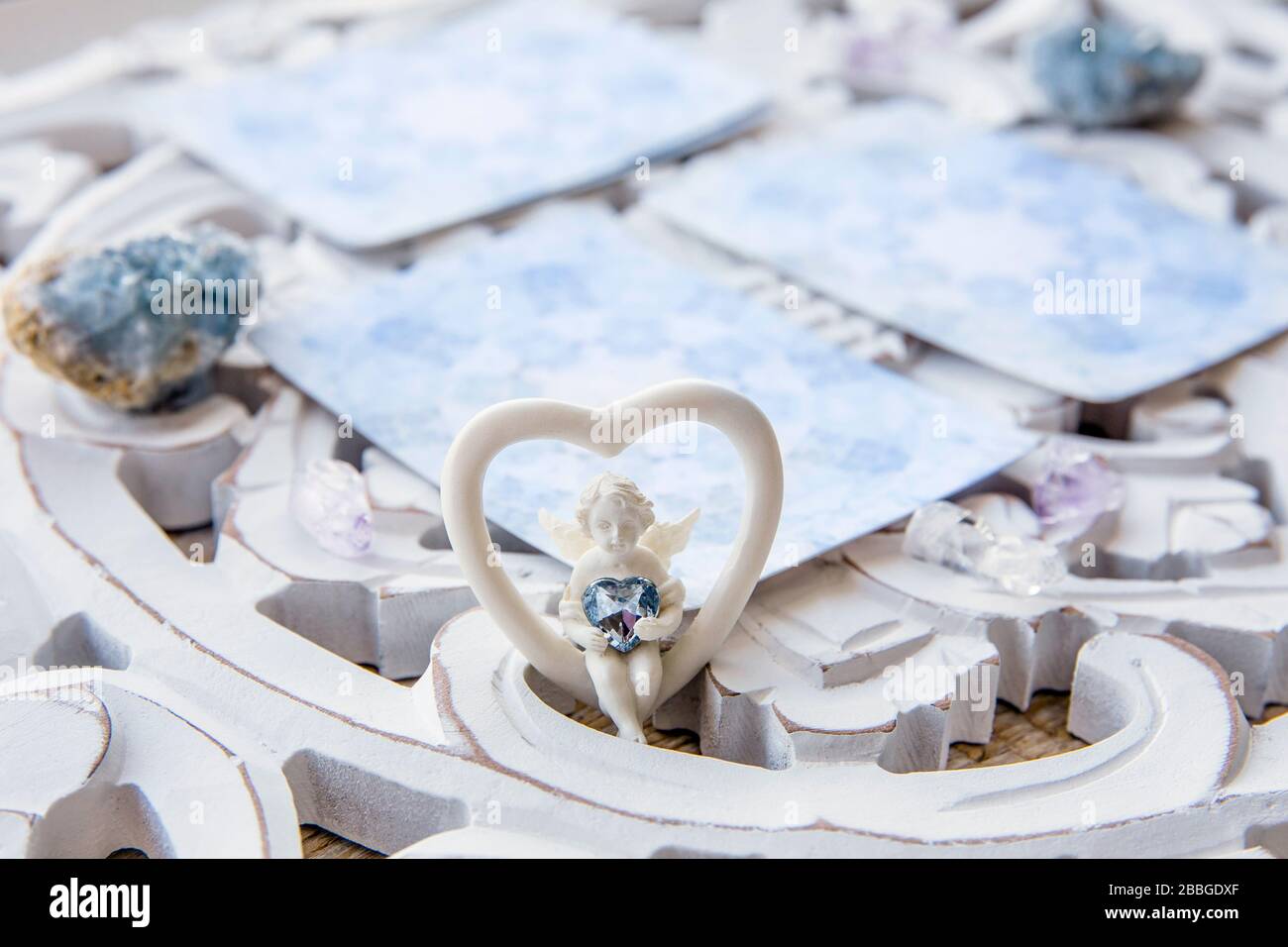 Terrasse avec divination faite maison cartes d'ange sur une table blanche vive, entourée de cristaux de pierres semi-précieuses. Foyer sélectif sur la figurine d'ange mignonne Banque D'Images