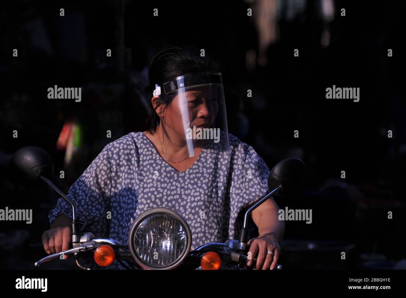 Une femme cambodgienne portant un masque fait sa moto à travers le marché de Kandal pendant la pandémie de coronavirus. Phnom Penh, Cambodge. © Kraig Lieb Banque D'Images