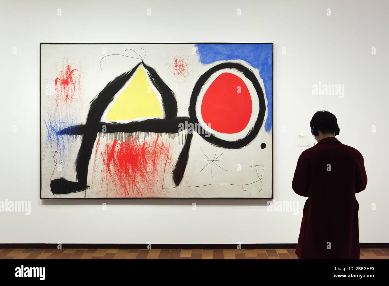Visiteur devant la peinture du peintre moderniste espagnol Joan Miró intitulée "Figure devant le soleil" (1968) exposé dans la Fundació Joan Miró (Fondation Joan Miró) à Barcelone, Catalogne, Espagne. Banque D'Images