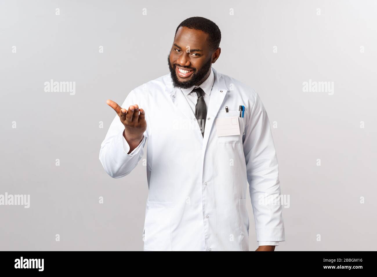 Enchanté de vous rencontrer, dites-moi votre problème. Portrait de médecin afro-américain poli et amical et charismatique invitant le patient à s'asseoir et à expliquer Banque D'Images