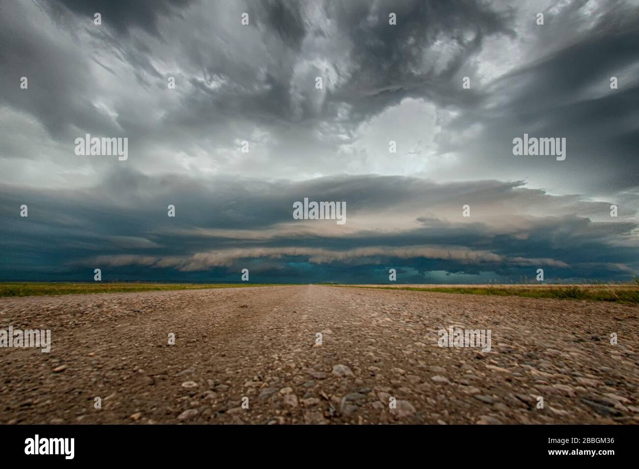 Tempête avec nuage de rayons sur la route rurale de gravier à Saskatchewan, Canada Banque D'Images