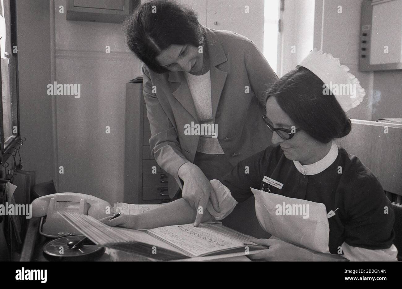 Années 1970, historique, une femme médecin avec infirmière sœur regardant les notes médicales d'un patient, Lewisham, South East London, Angleterre, Royaume-Uni. Banque D'Images